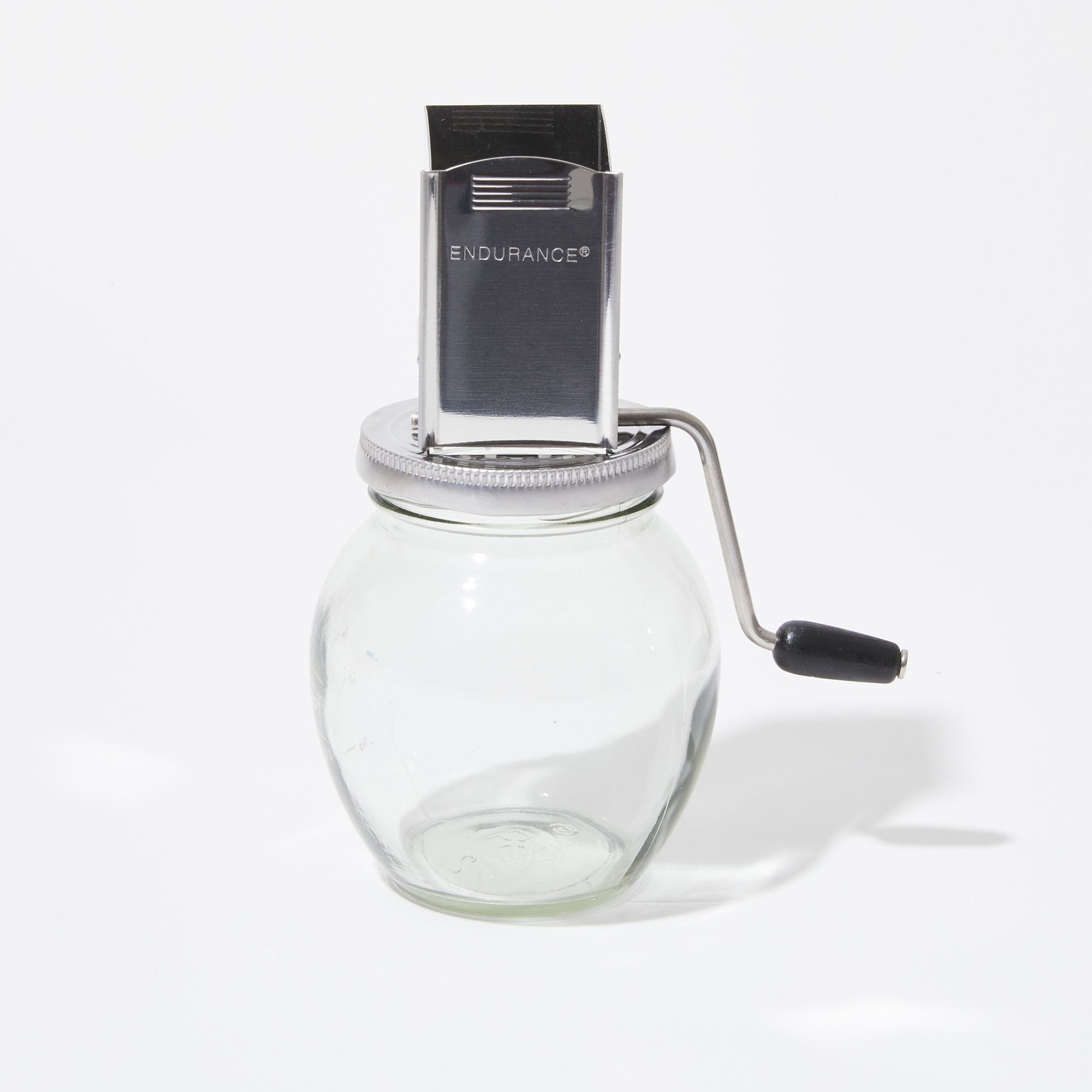 Square metal shute with a S-curved crank handle atop a clear round glass jar