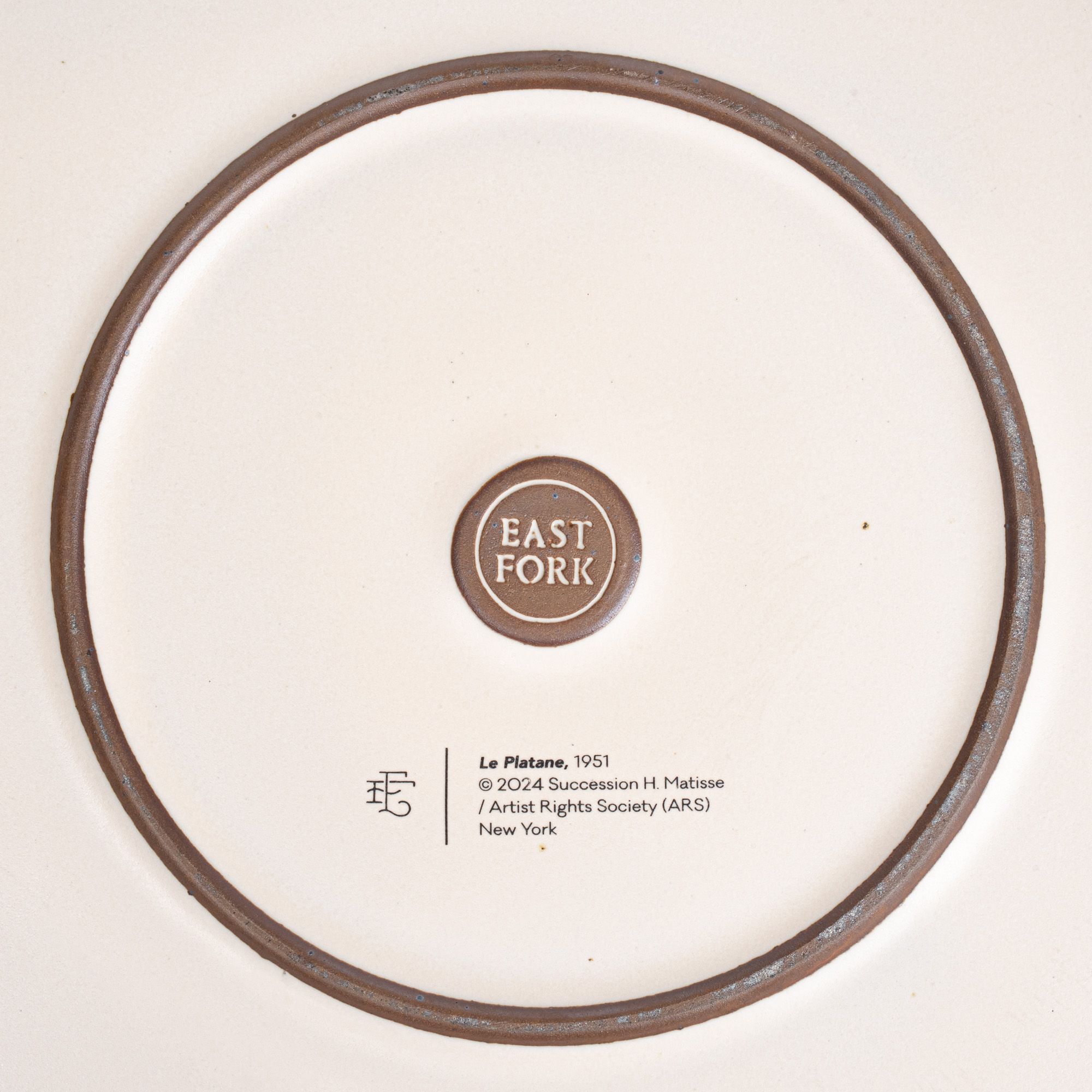 The back of the Serving Platter with an East Fork stamp with a small decal of information about the artwork.