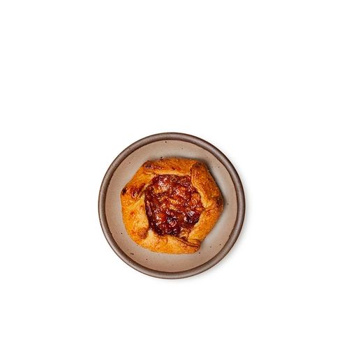 A galette on a dessert sized ceramic plate in a warm pale brown color featuring iron speckles and an unglazed rim.