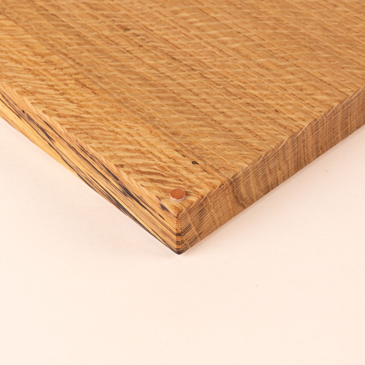 Close up of a corner of thick rectangular cutting board made of light-colored wood
