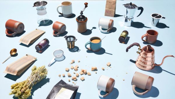 hands holding the small mug, the mug and the big mug around a stuck of different sized mugs