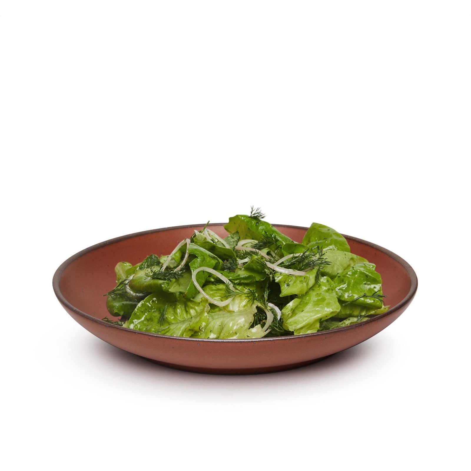 A burnt red (amaro) colored dish with a simple green salad on top. The dish is not quite a bowl, not quite a plate. It has rounded edges to keep dressing and sauce from dipping off the side.