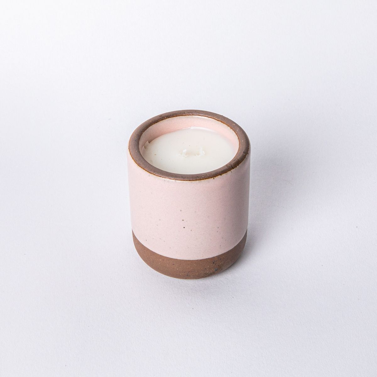 Small ceramic vessel in soft light pink color with candle inside