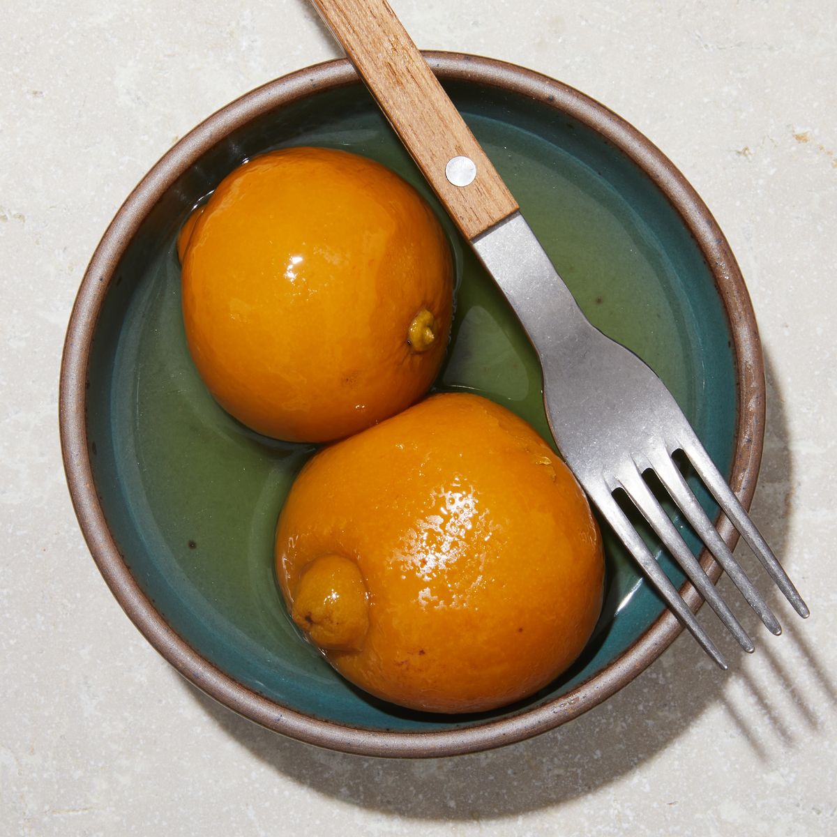 Two halves of a preserved lemons on a plate next to a fork