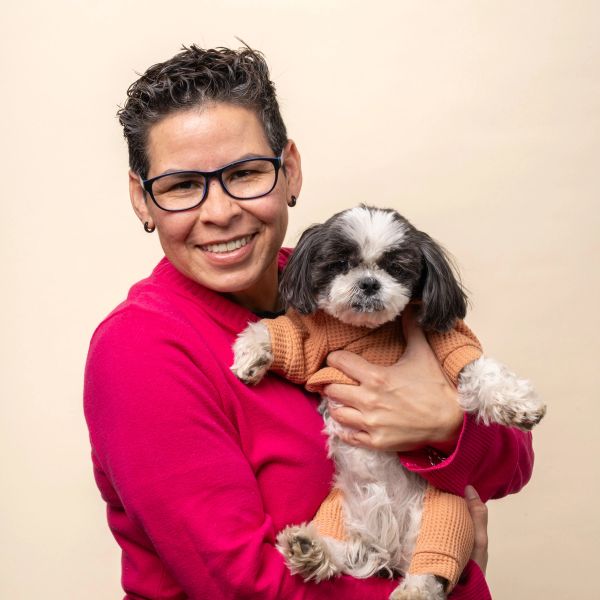 A headshot of Karla V. holding her small dog