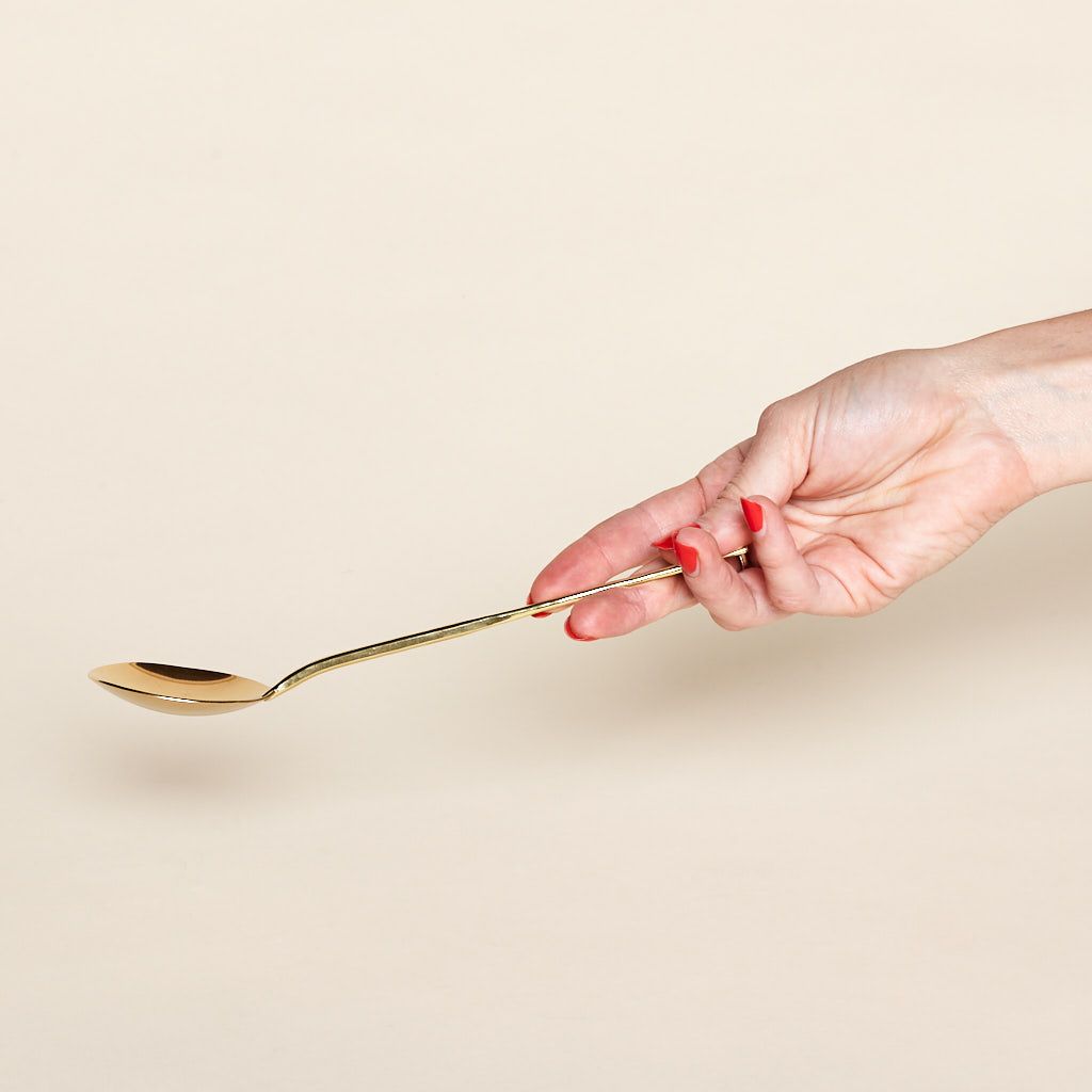 A hand extends a brass serving spoon.