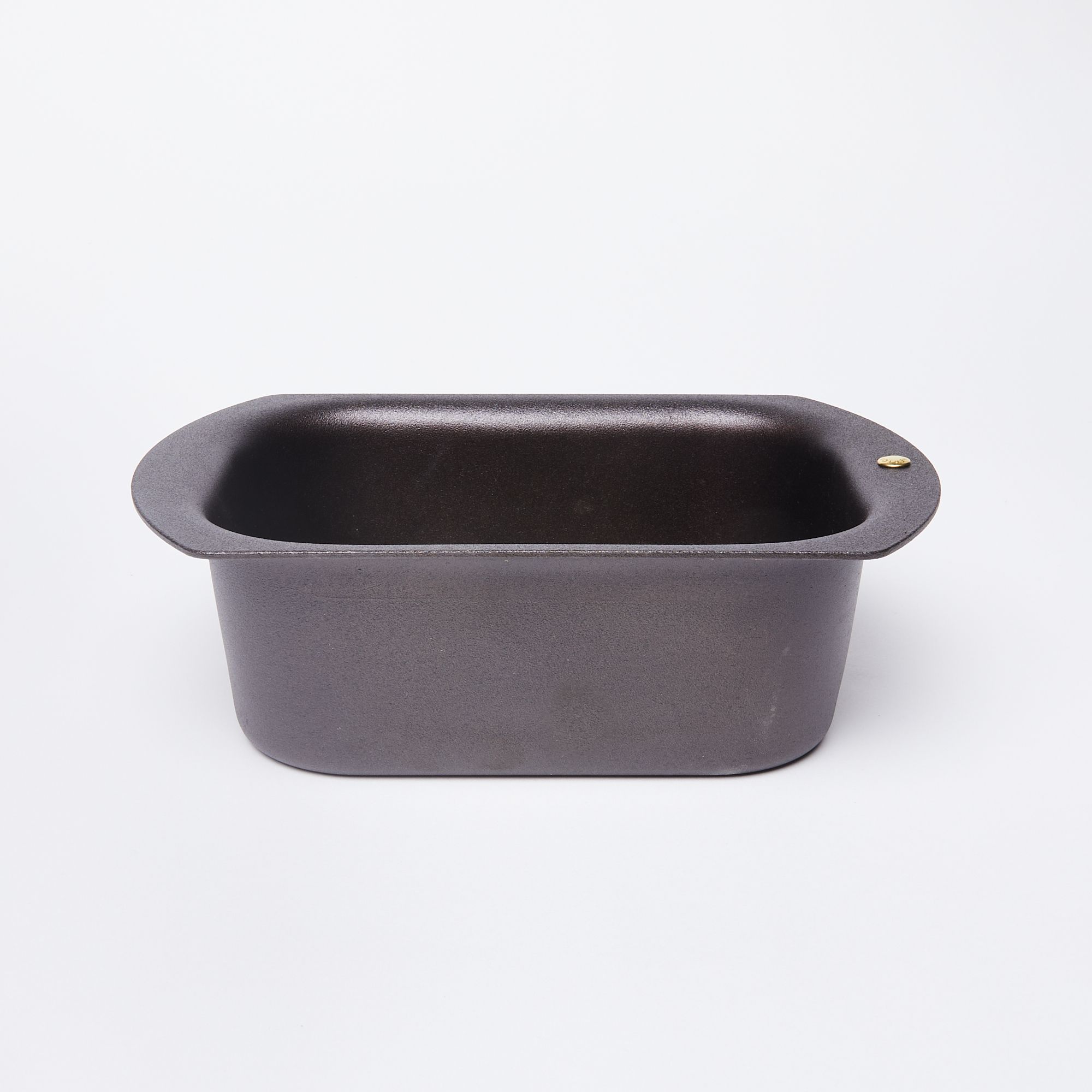 A black metal loaf pan with rounded corners and a wide flat lip