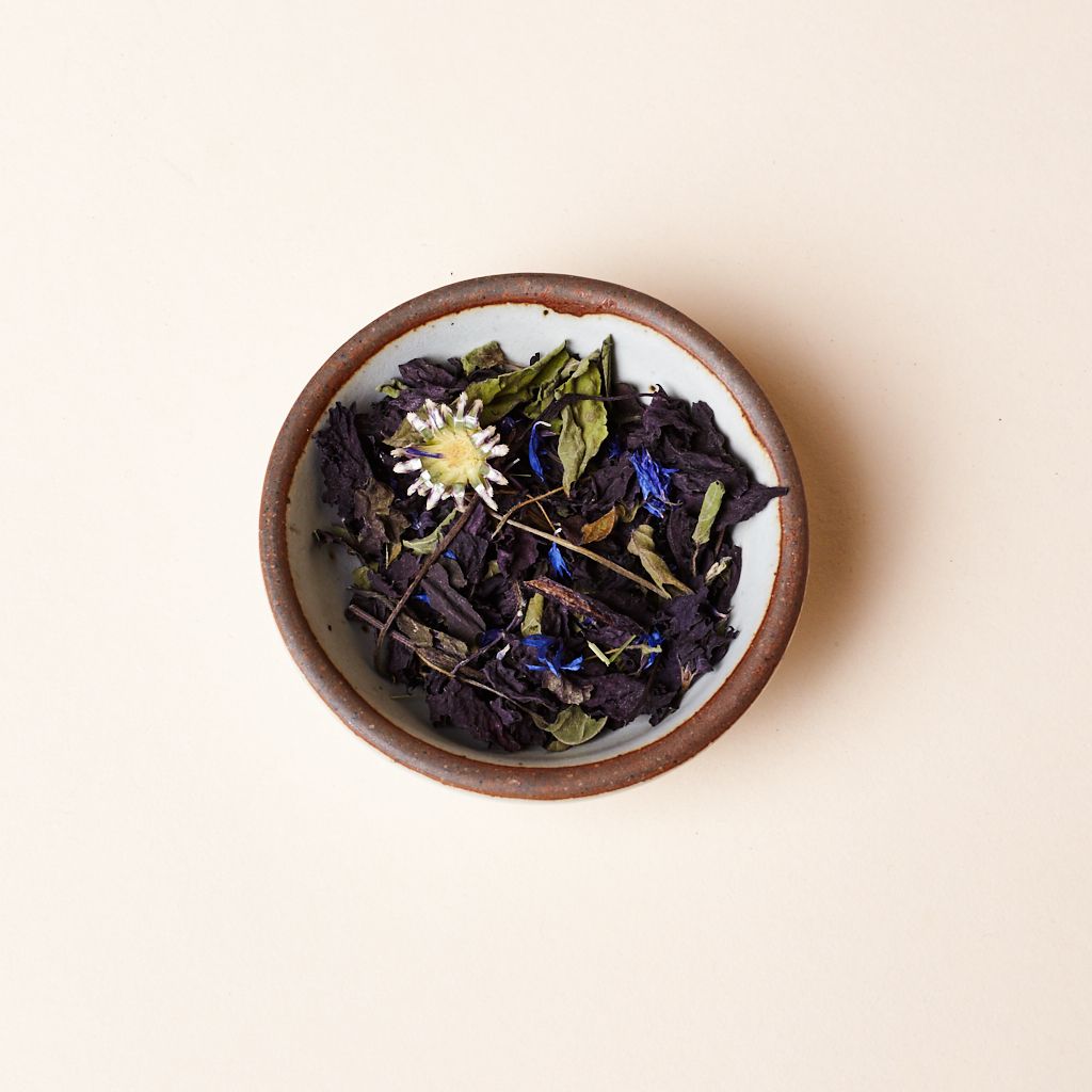 An eggshell bitty bowl holding loose leaf tea leaves
