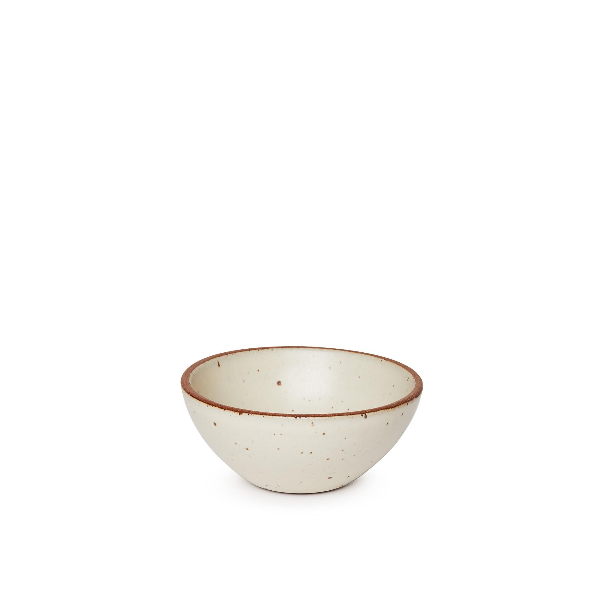 A small dessert sized rounded ceramic bowl in a warm, tan-toned, off-white color featuring iron speckles and an unglazed rim