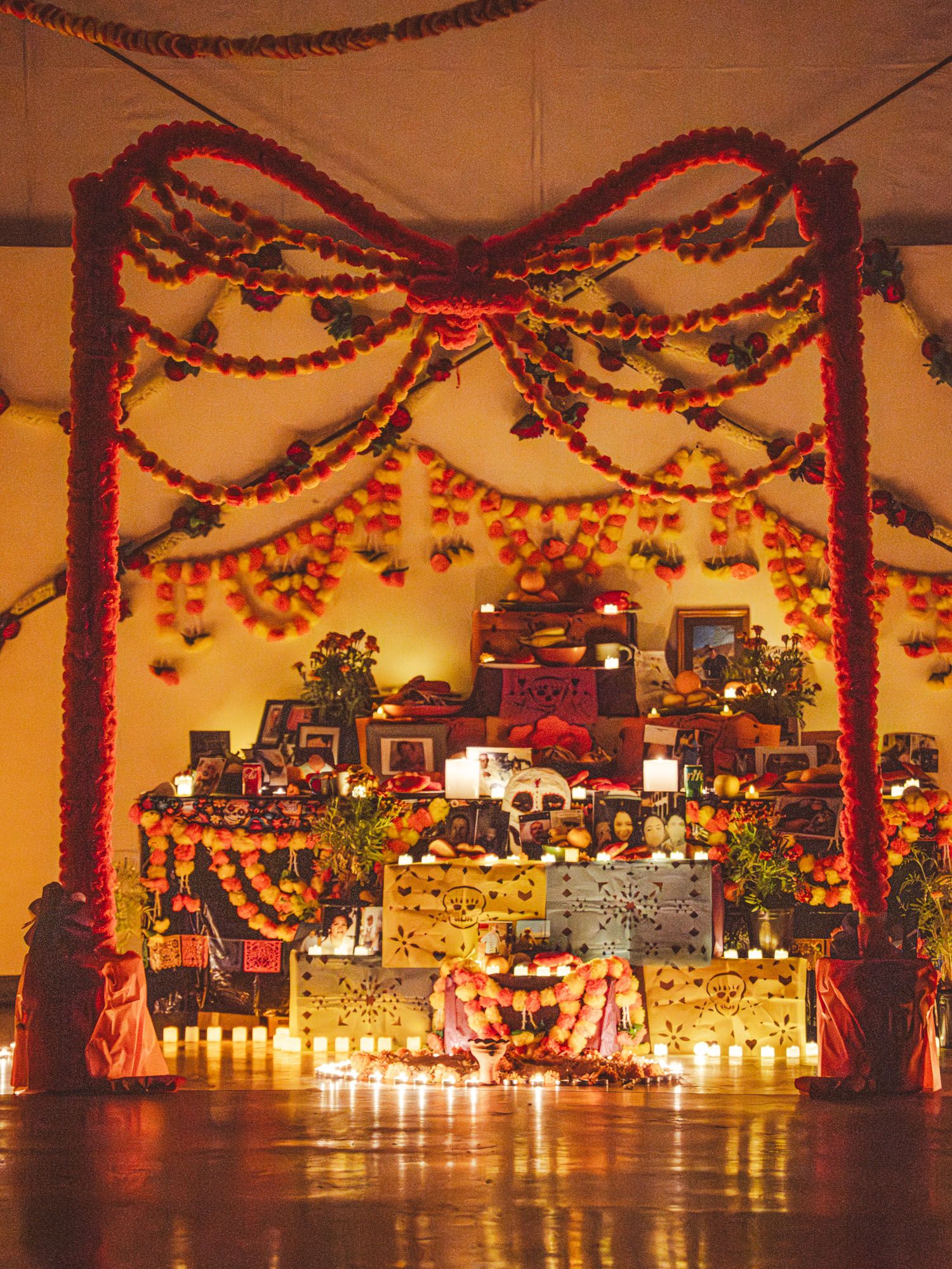 A highly decorated altar of photos decorated with florals and glowing with candlelight