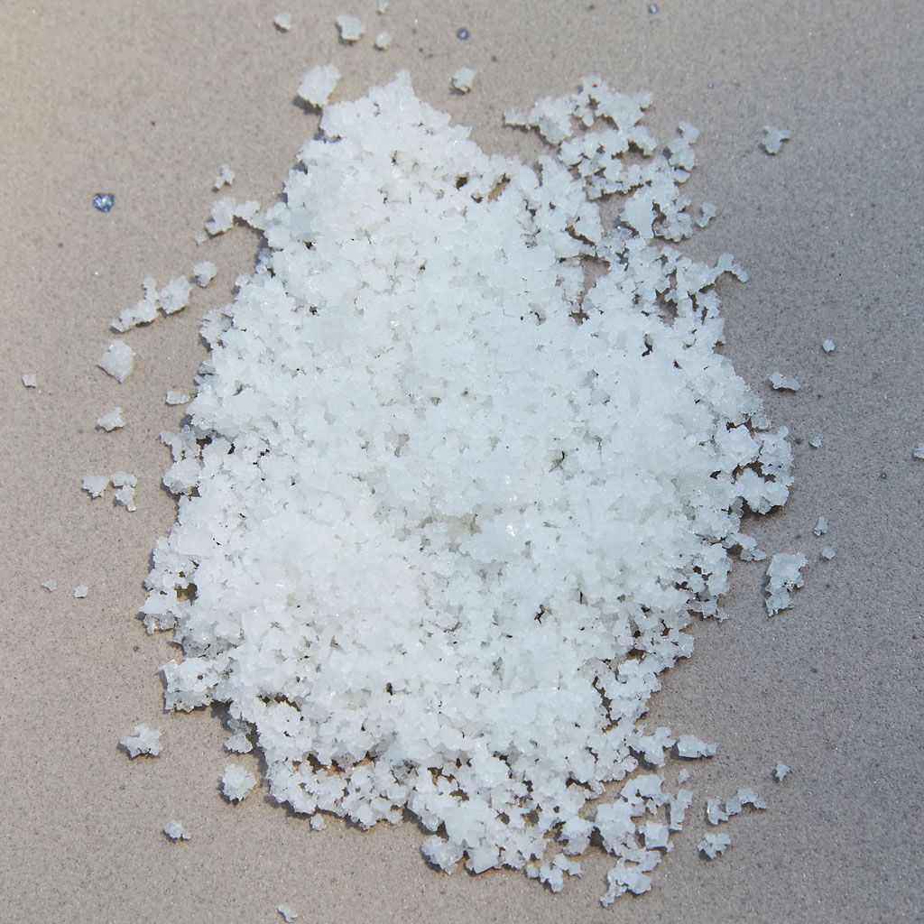 Grains of white salt on a light brown background 