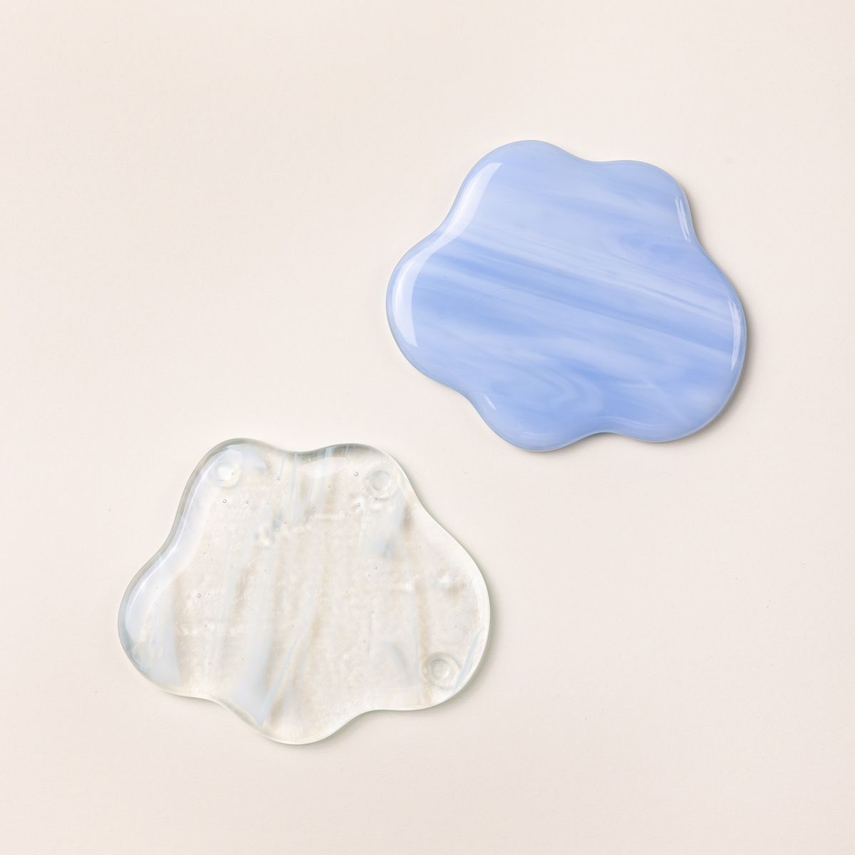 2 glass coasters shaped like clouds in a translucent clear, and a periwinkle color