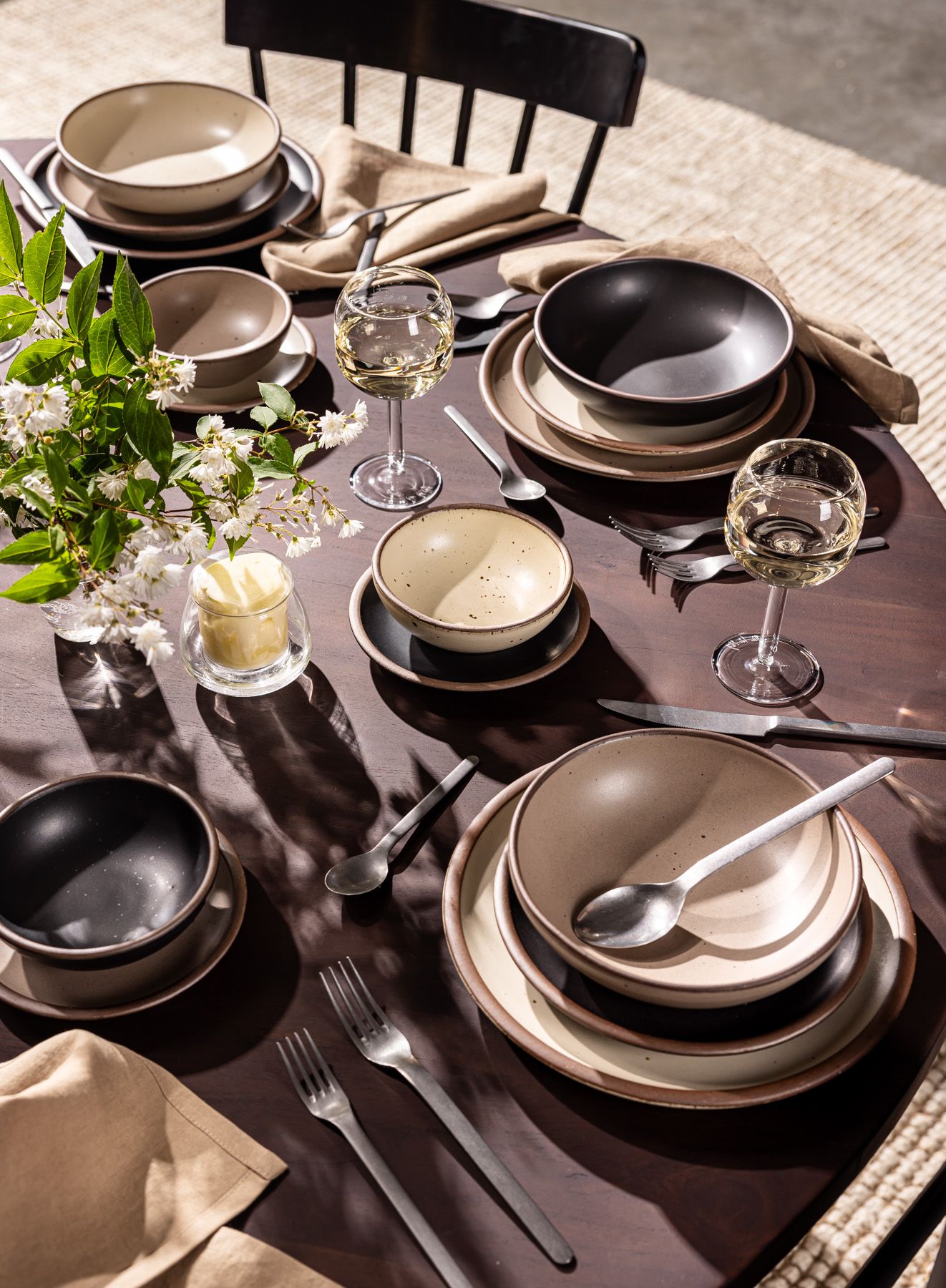 An artful display of cream and white ceramic plates with foods like whole eggs, garlic, and mushrooms