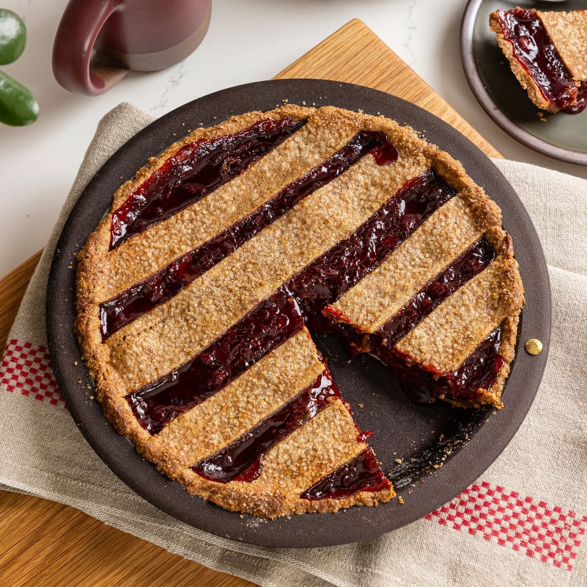 A pie with a slice taken out in a iron pie dish on a kitchen shelf