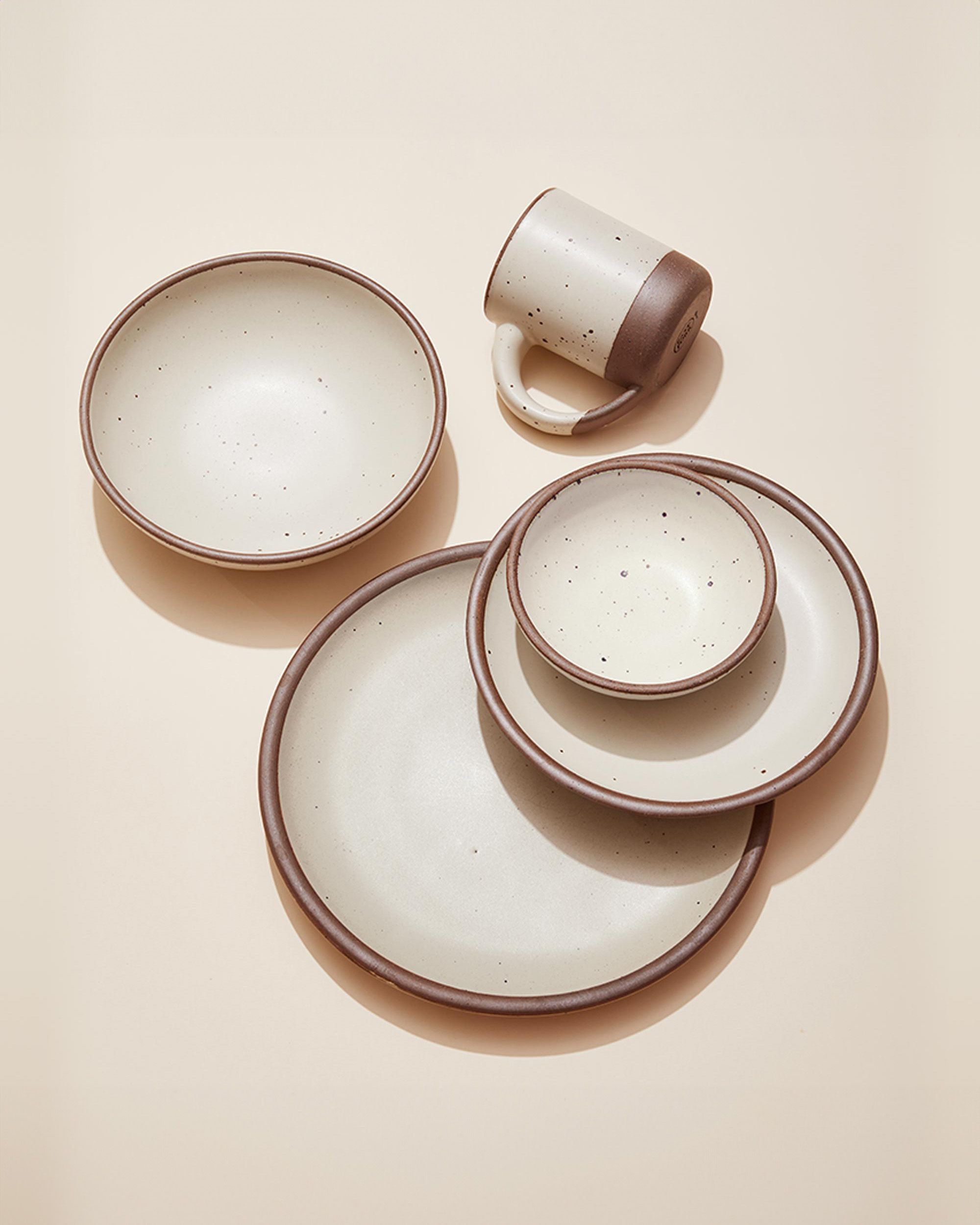 An artful arrangement of ceramic plates and a mug in a cream off-white color.