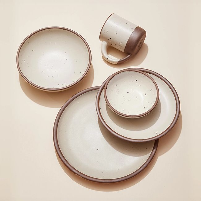 An artful arrangement of ceramic plates and a mug in a cream off-white color.