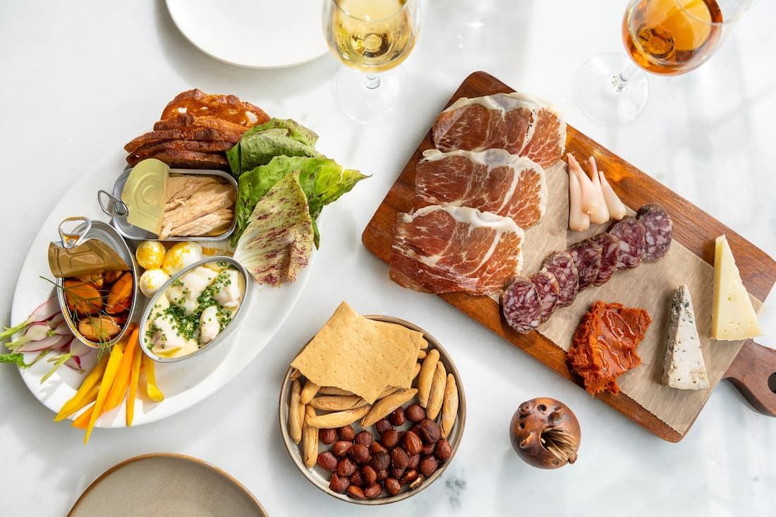 A spread of charcuterie and vegetables on a white tablecloth