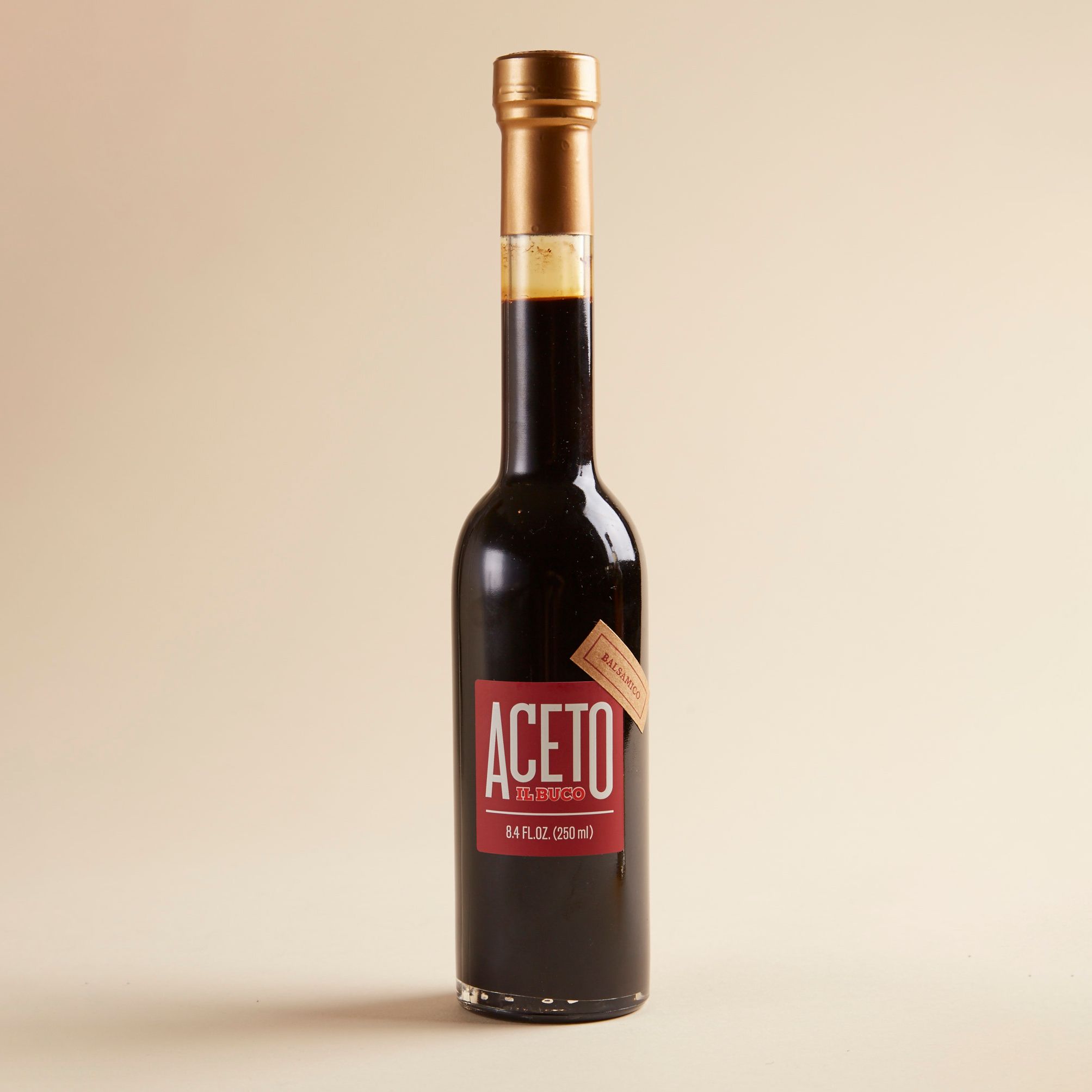 A dark brown narrow bottle with a red label that reads "Aceto Balsamic"