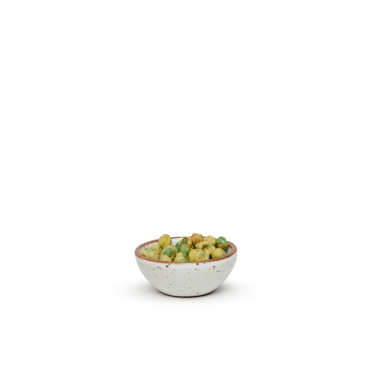 A tiny rounded ceramic bowl in a cool white color featuring iron speckles and an unglazed rim, filled with wasabi peas