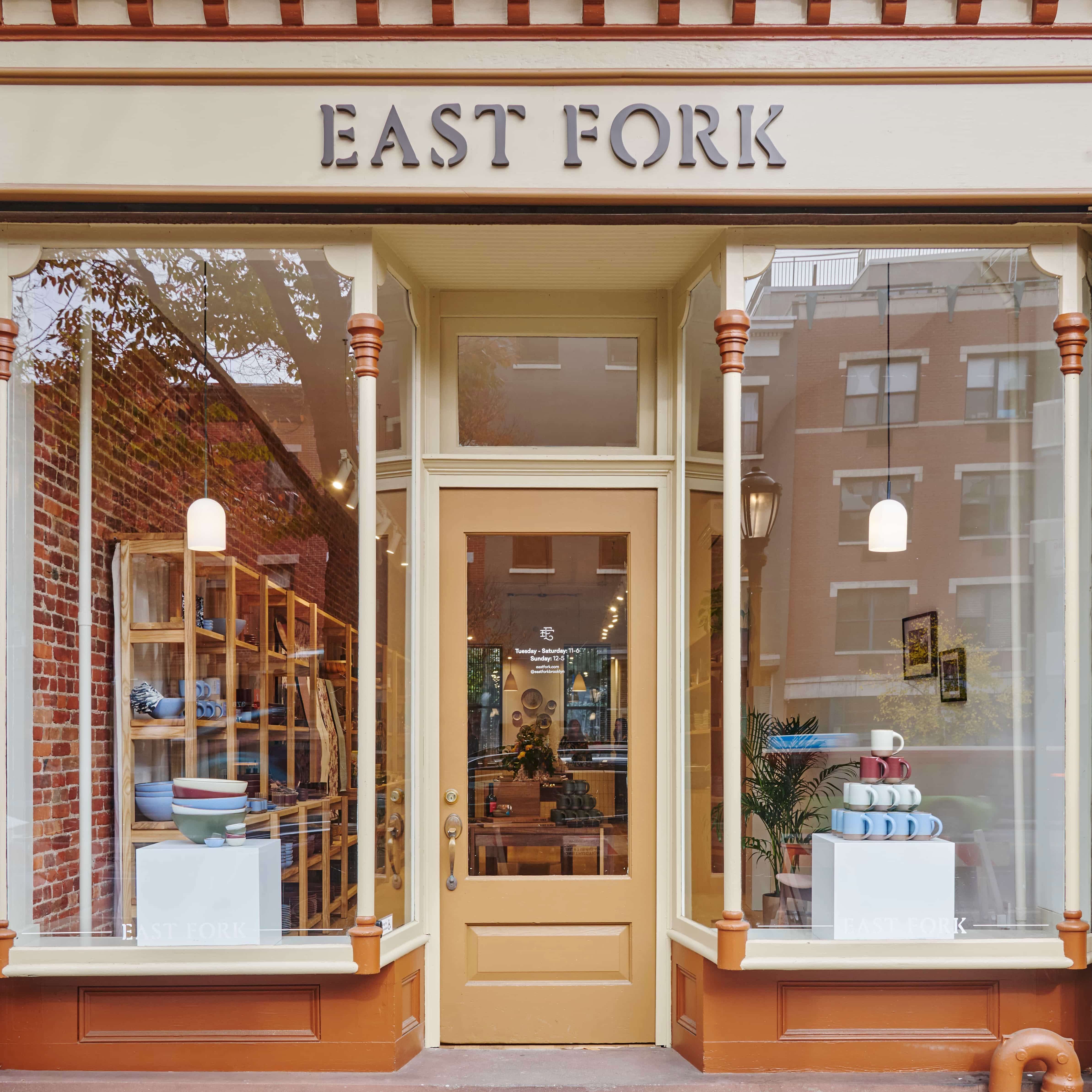 Exterior view of our East Fork Brooklyn storefront complete with 2 large windows and a brown door in the center with a sign overhead that reads 'East Fork'