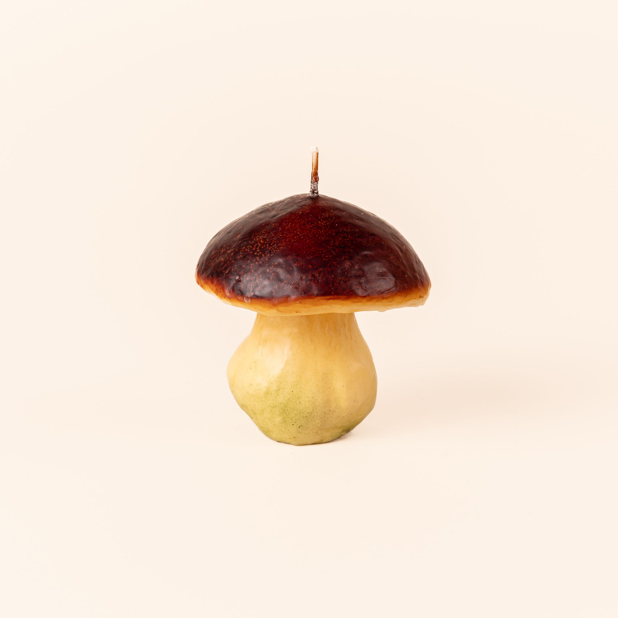 A candle that looks like a wild mushroom with a dark red top.