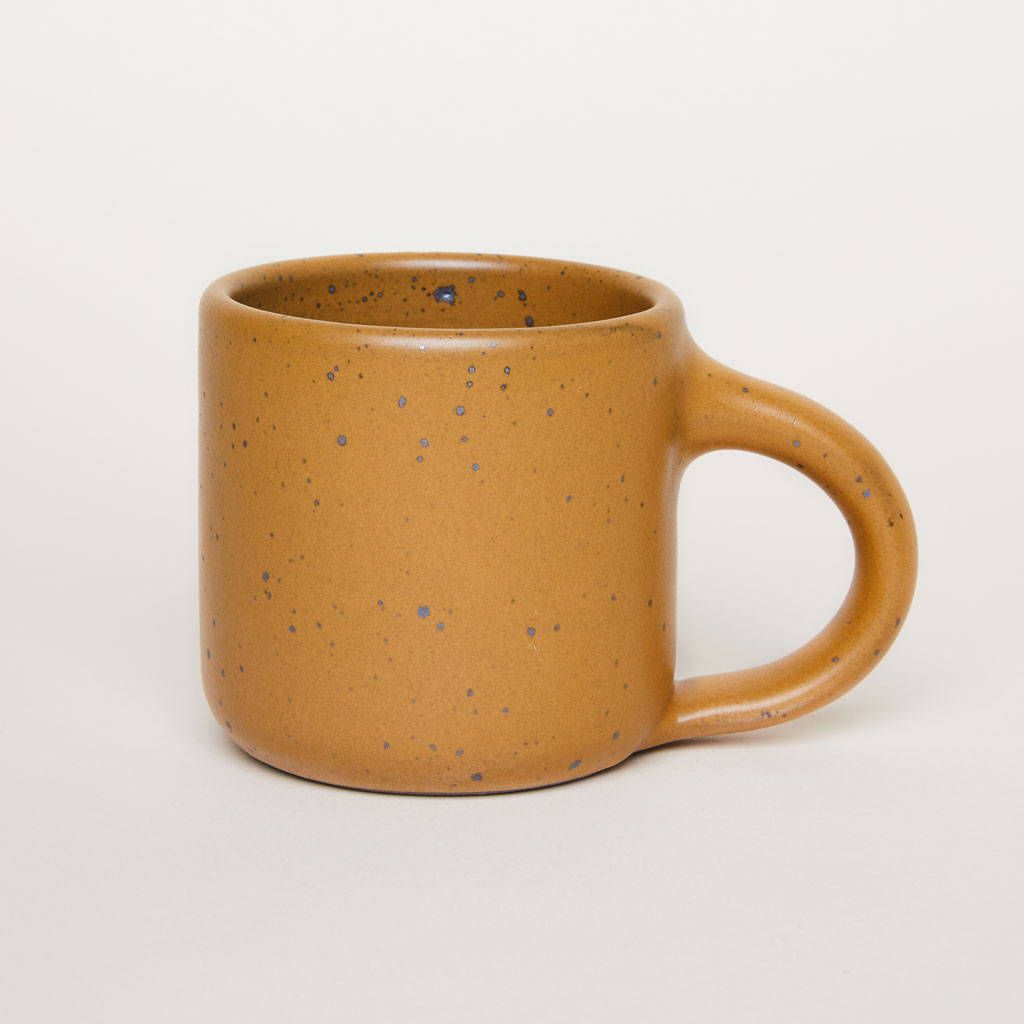 A medium sized ceramic mug with handle in a dark gold color featuring iron speckles