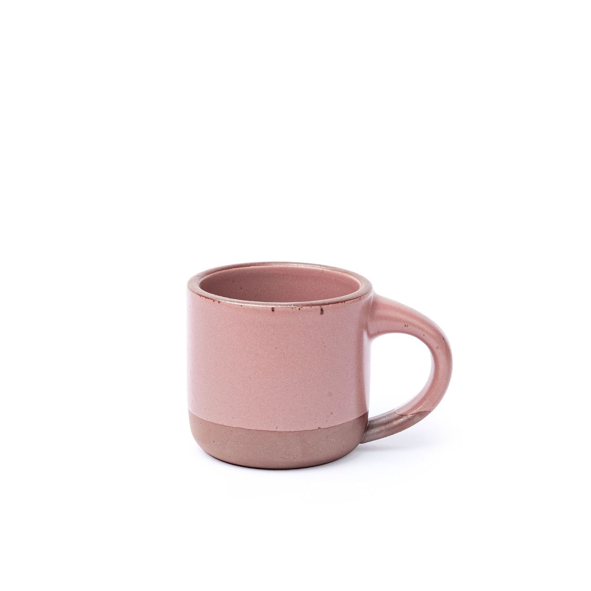 A small sized ceramic mug with handle in a dusty mauve pink glaze featuring iron speckles and unglazed rim and bottom base.