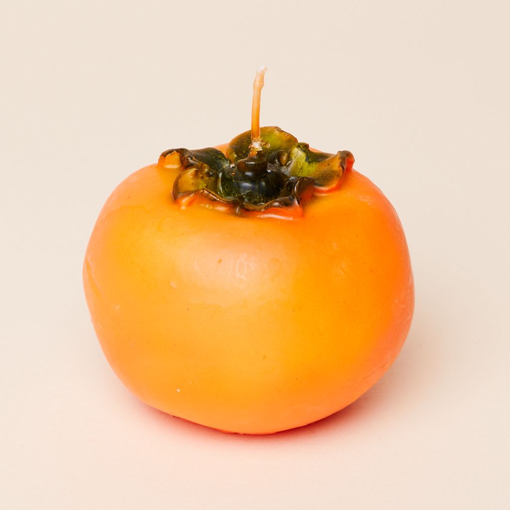 An orange and green candle that looks like a whole persimmon