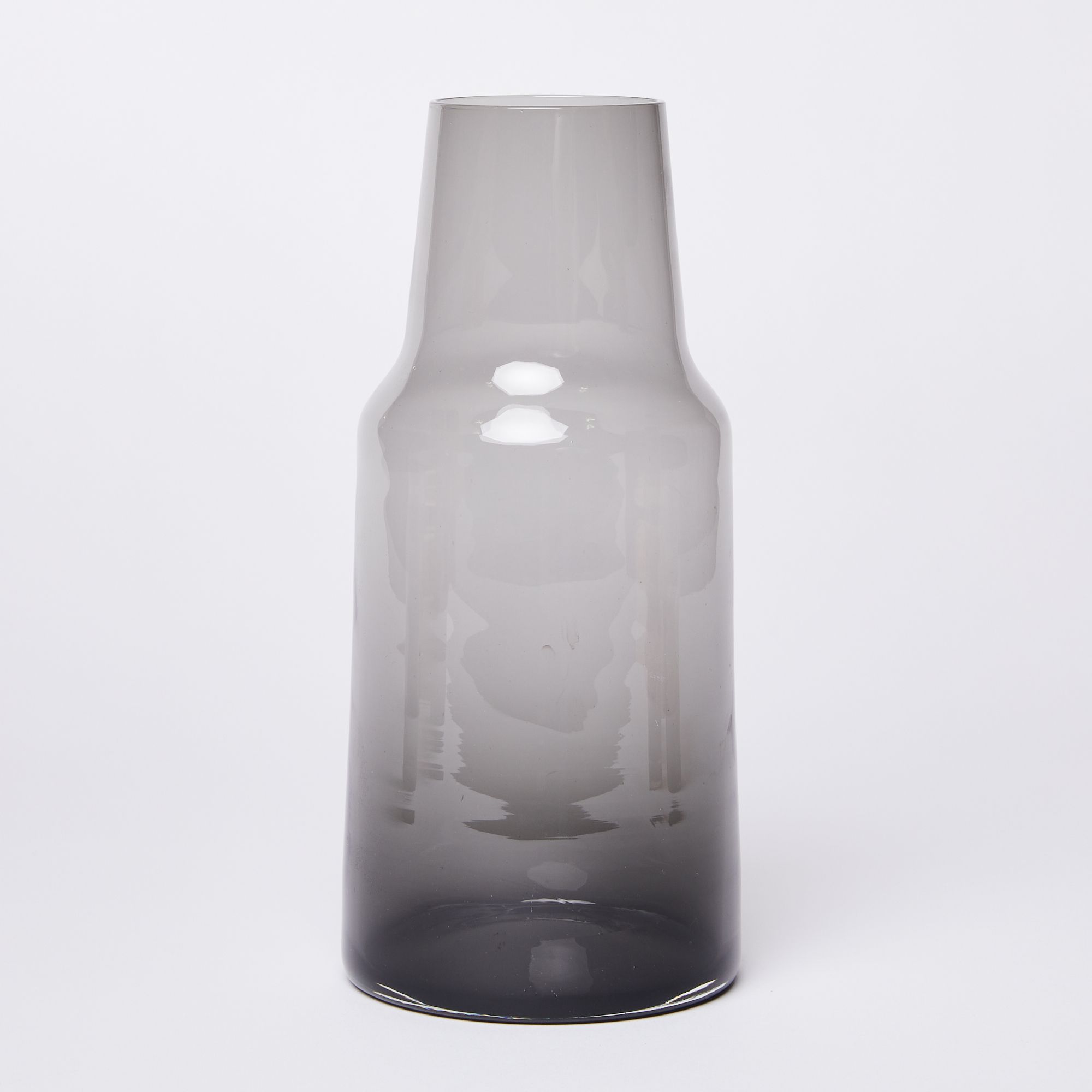 Glass carafe tapering at the top with a dark black bottom getting lighter grey towards the top