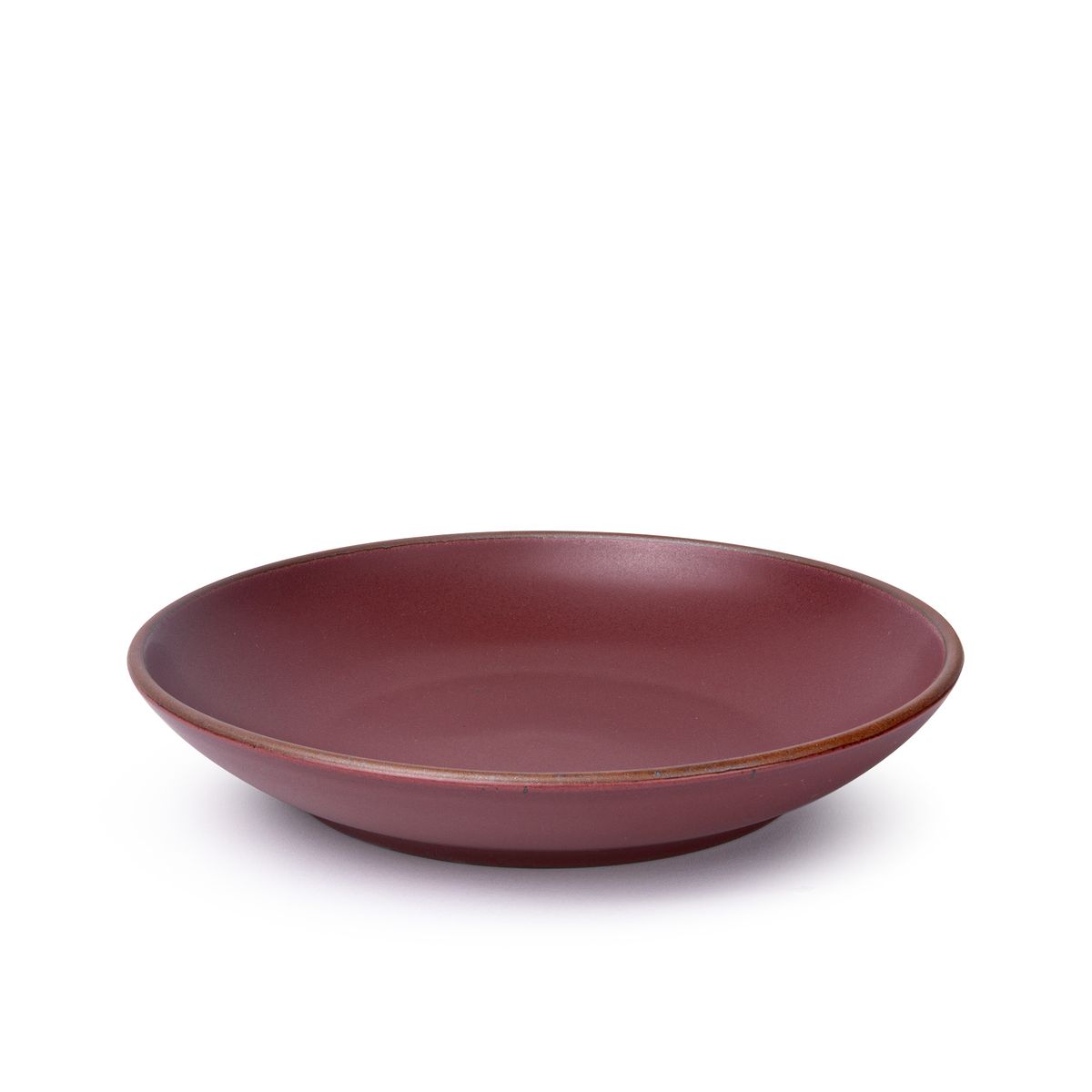 A large ceramic plate with a curved bowl edge in a plum color featuring iron speckles and an unglazed rim.