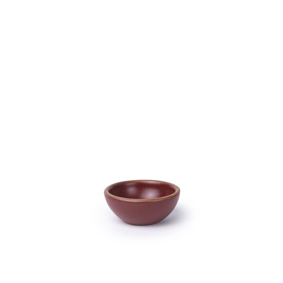 A tiny rounded ceramic bowl in a plum color featuring iron speckles and an unglazed rim