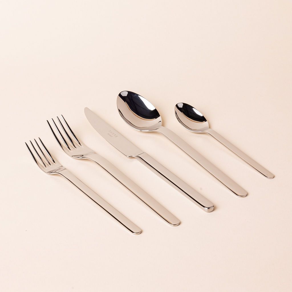 Classic minimal shiny stainless steel flatware arranged in a row with a salad fork, dinner fork, knife, spoon, and soup spoon.