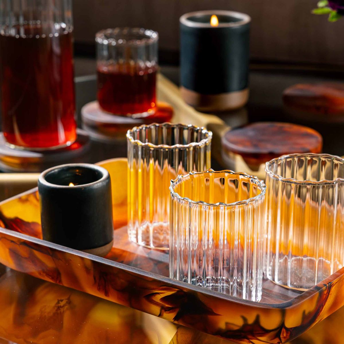 Three fluted clear glasses sit on a tortoiseshell tray