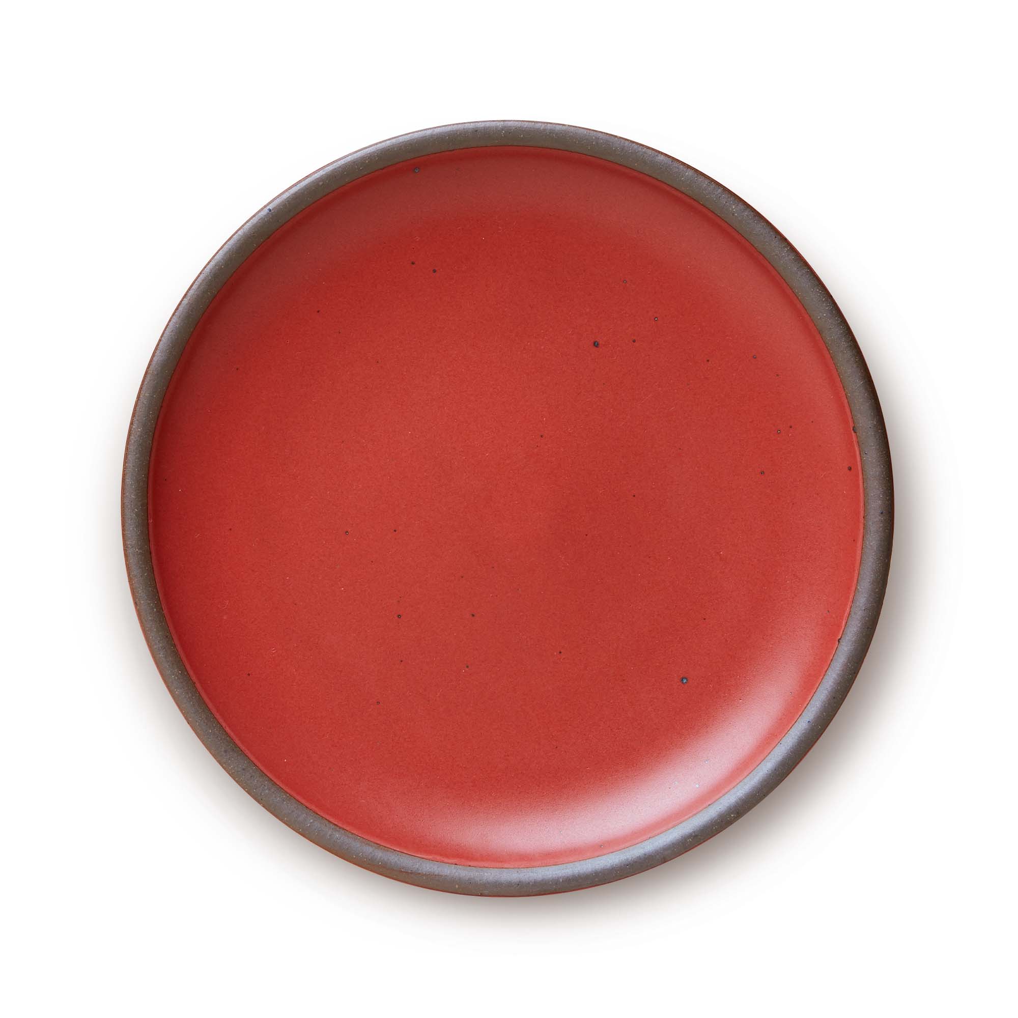 A large ceramic platter in a deep red color featuring iron speckles and an unglazed rim.