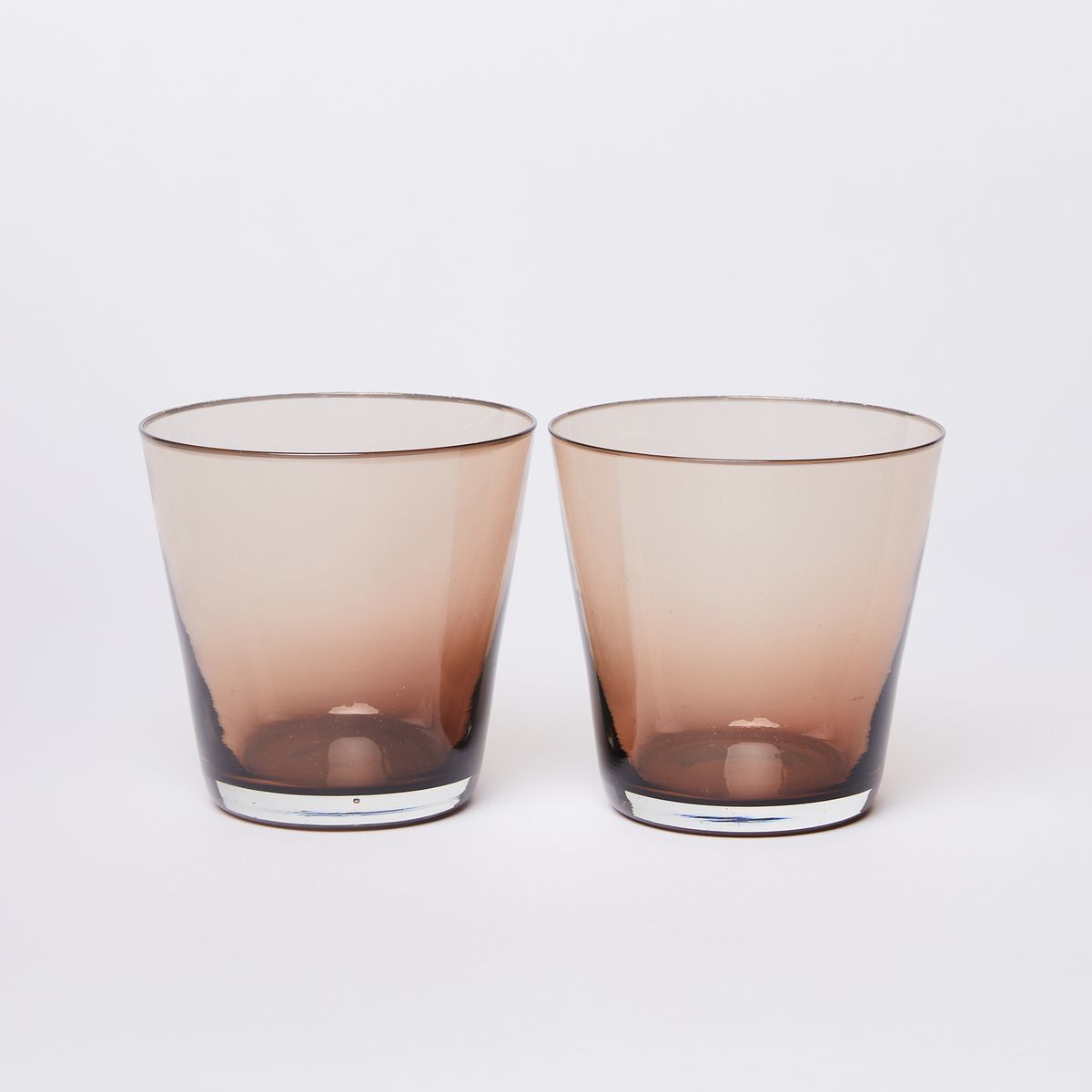 Two glass tumblers that with a brown gradient that lightens towards the wider rim