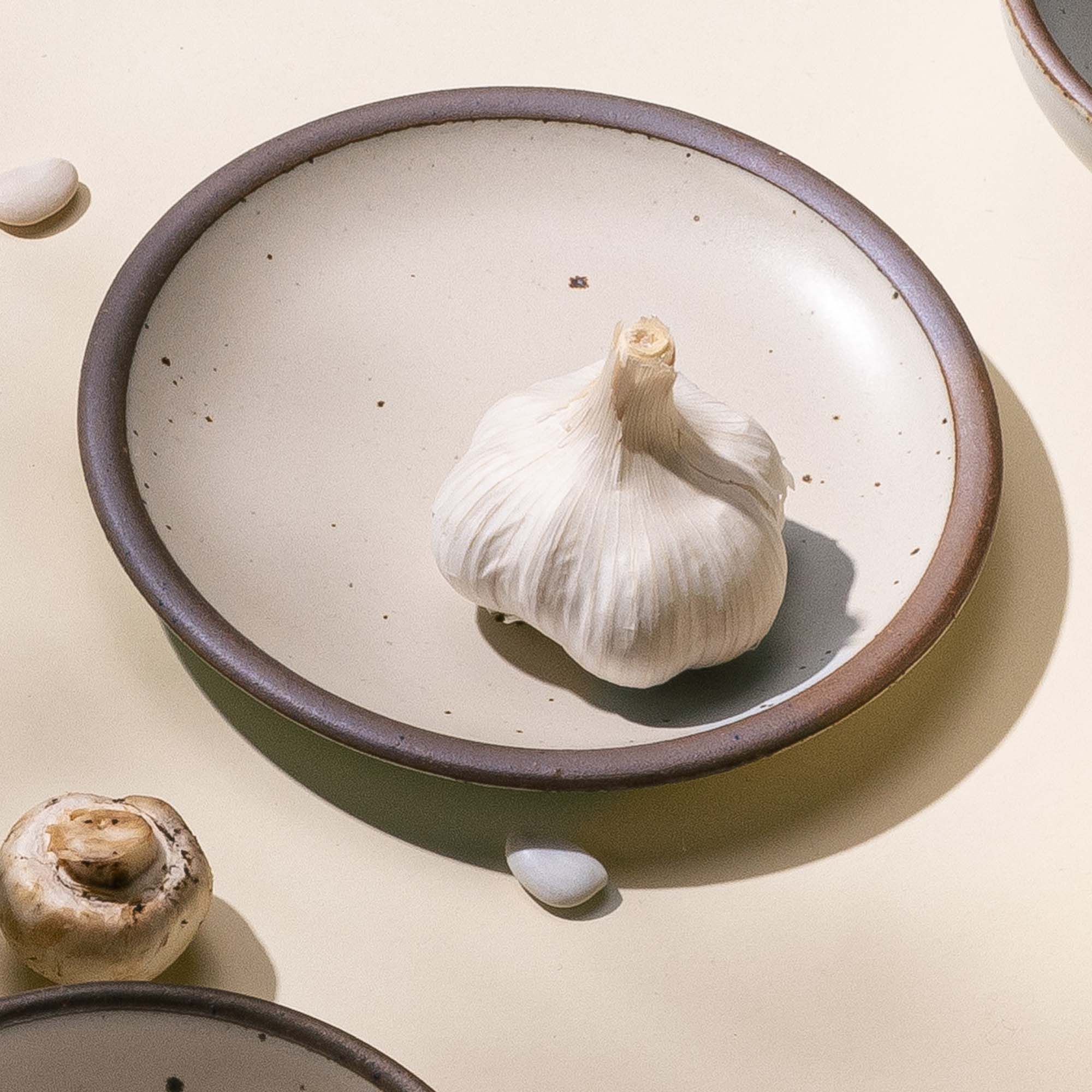 A small ceramic dessert plate with a garlic bulb sitting on it