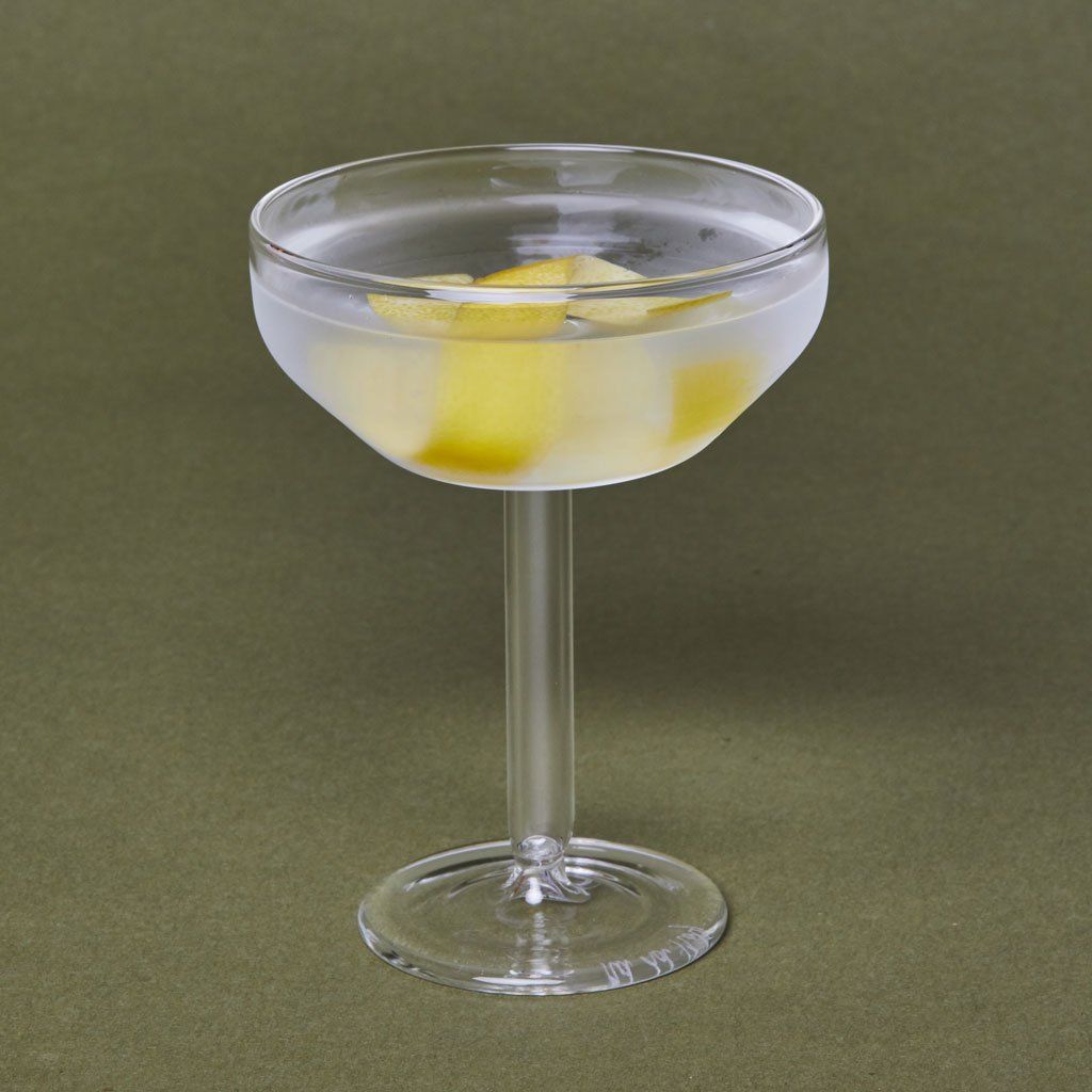 One clear glass Martini coupe filled with chilled, clear liquid and a twist of lemon