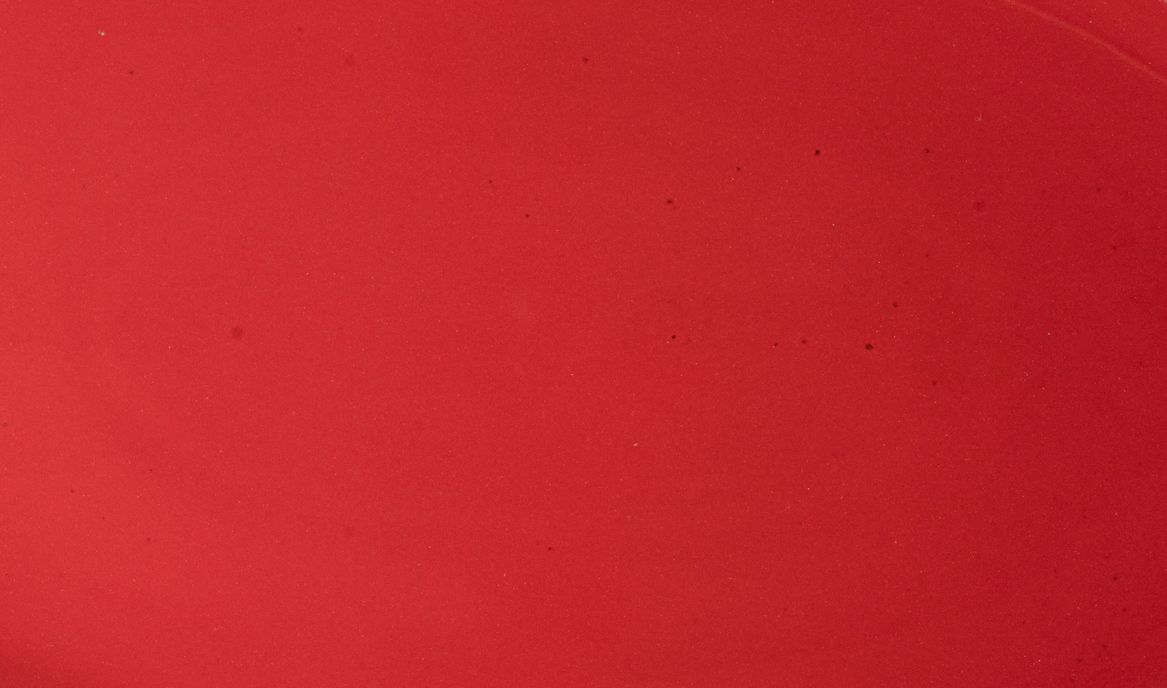 Closeup of a glossy red plate with subtle iron speckles