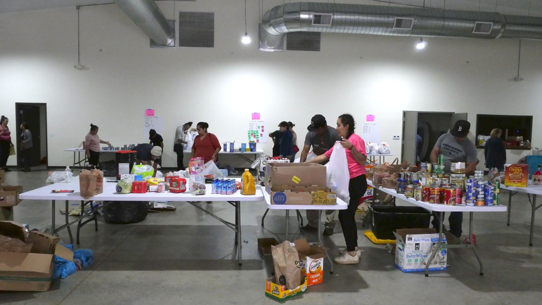 Indoors, tables are filled with donations like canned goods and volunteers surrounding to assist in the Hurricane Helene relief.