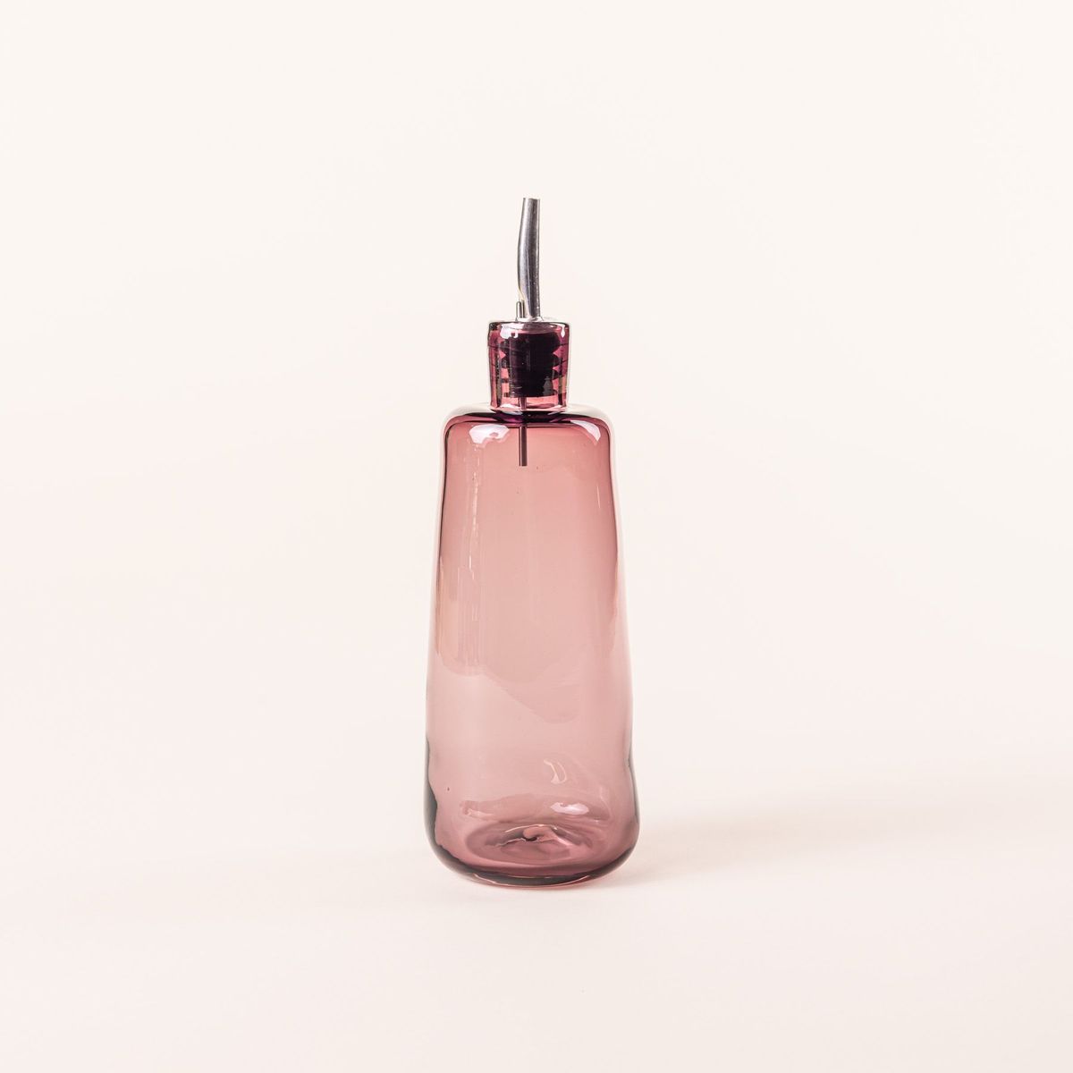 A tall glass cylindrical cruet in a light plum color