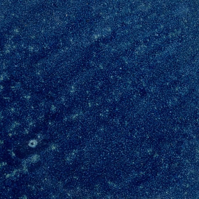 A closeup of a ceramic plate in a reflective dappled deep blue color