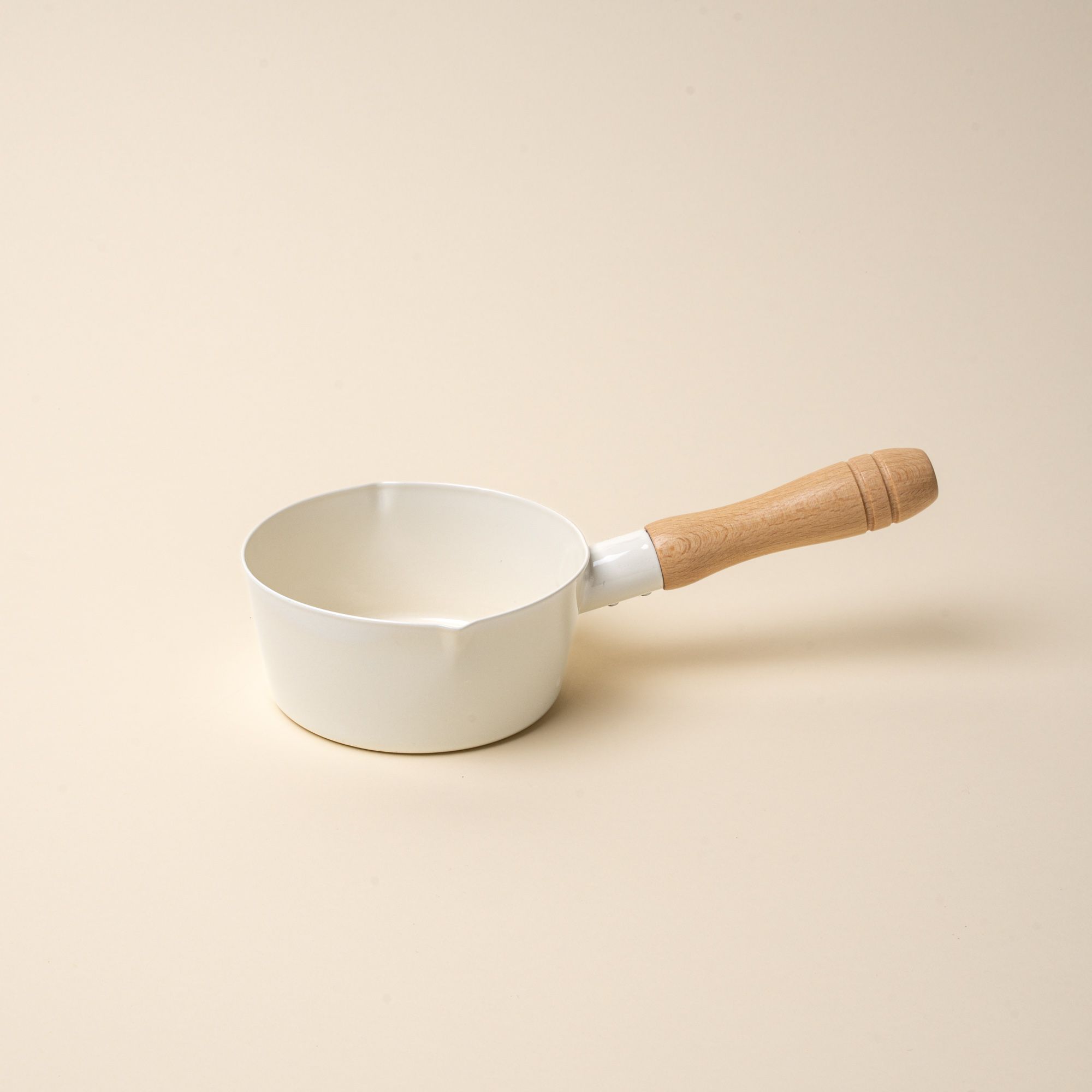 A white enamel pot with simple spouts on the side with a wooden handle