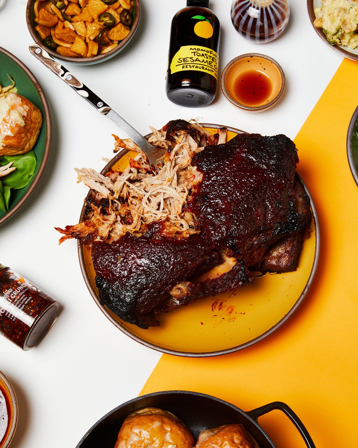 An artful overhead view of Bo Ssäm on a golden yellow ceramic plate, surrounded by ingredients and side dishes.