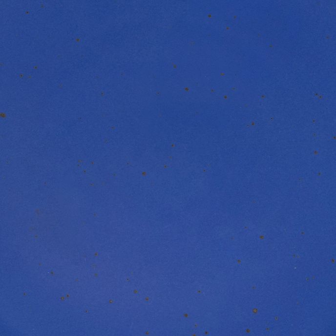 A closeup of a ceramic plate in a cobalt blue color with iron speckles throughout