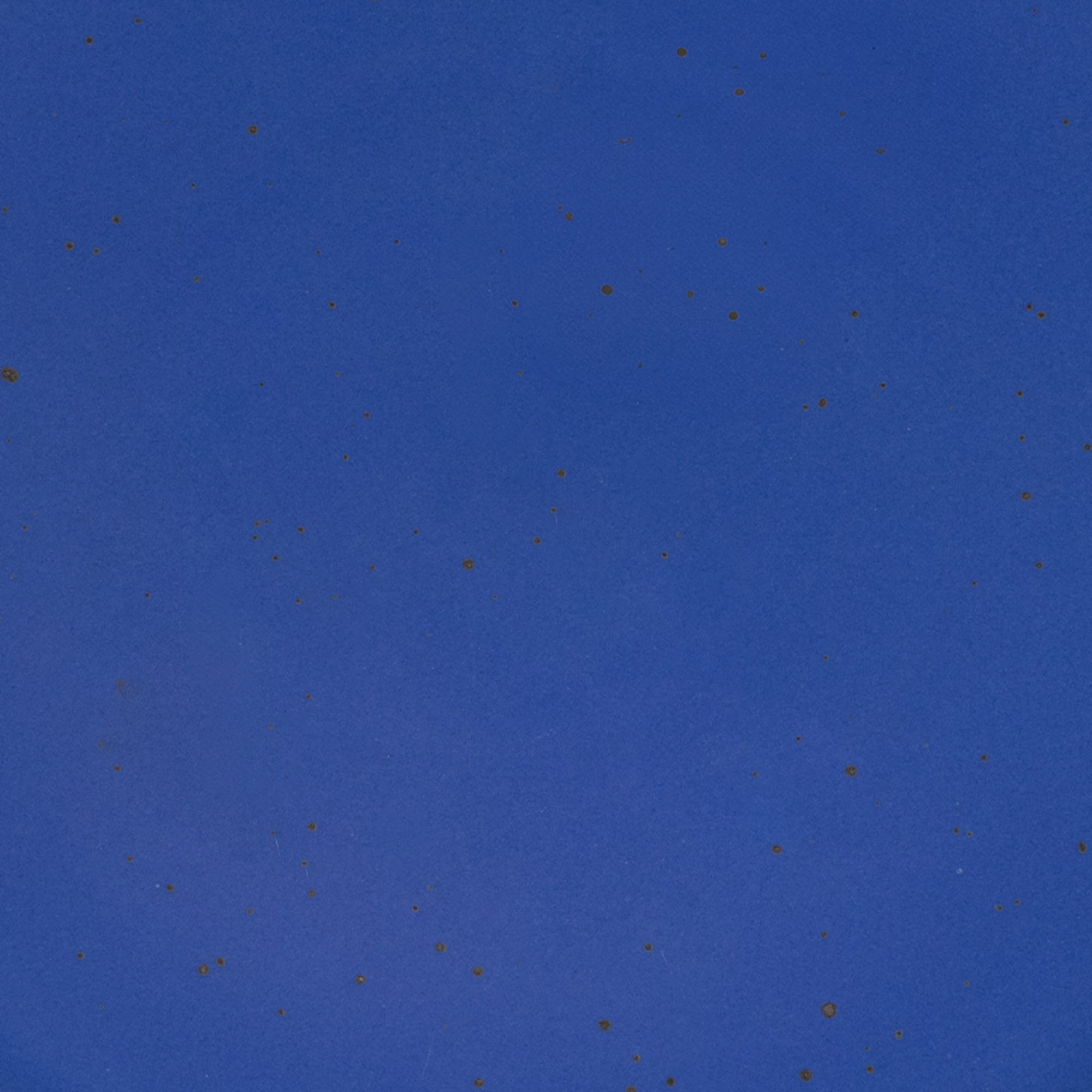 A closeup of a ceramic plate in a cobalt blue color with iron speckles throughout