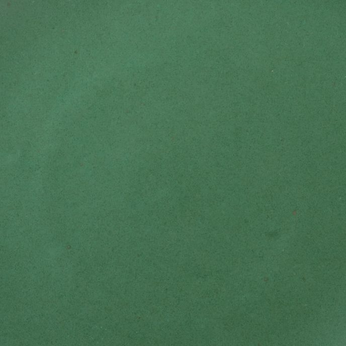 A closeup of a ceramic plate in a true green color featuring subtle iron speckles