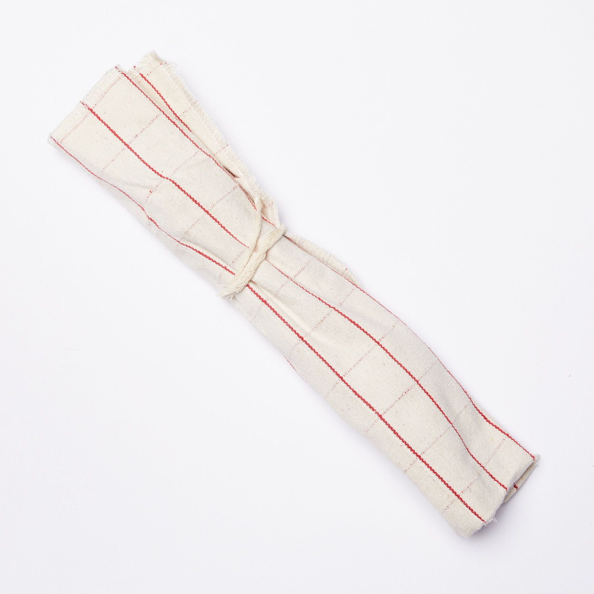 Utensil roll, made of cream color fabric with a thin red grid pattern, tied with a string