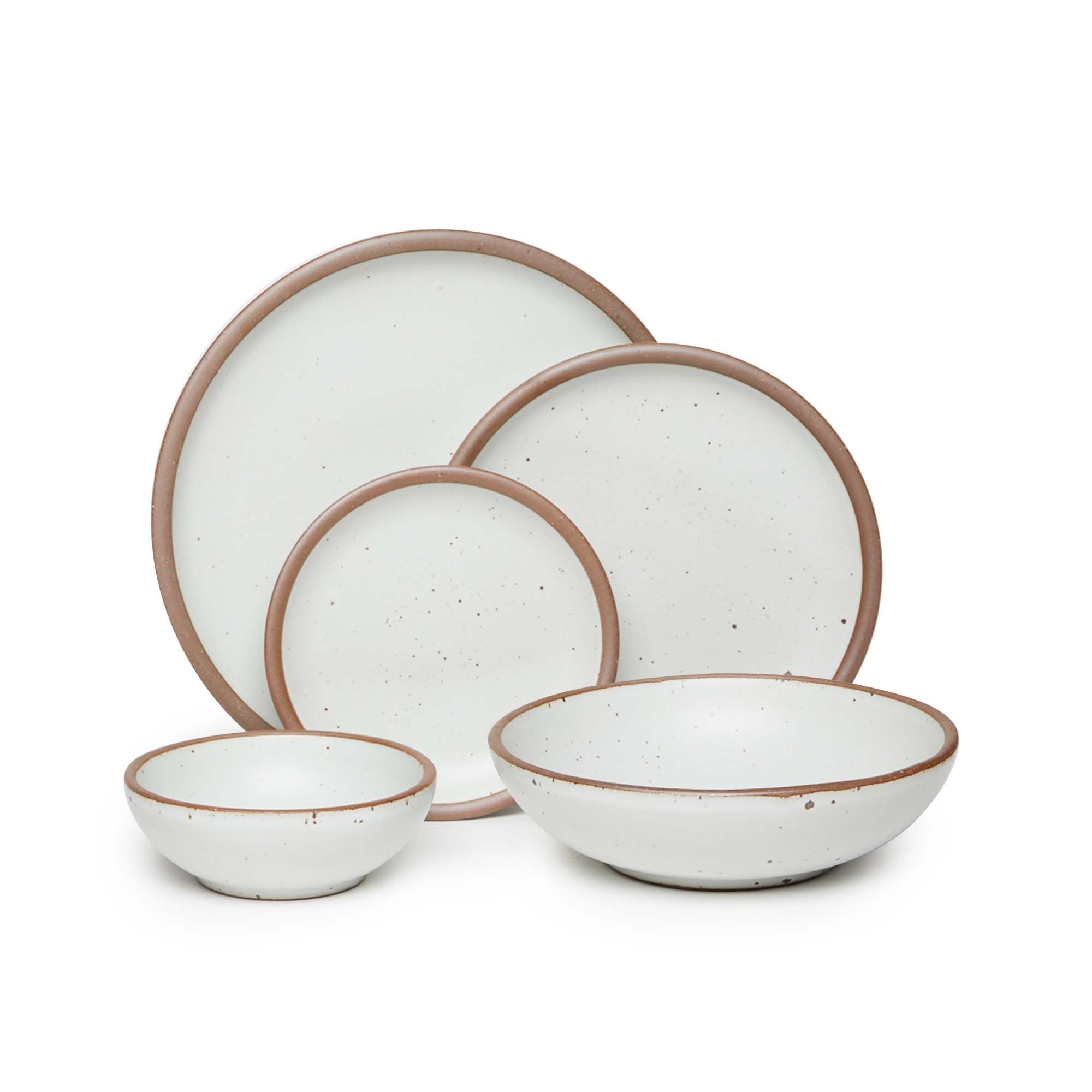 A breakfast bowl, everyday bowl, cake plate, side plate and dinner plate paired together in a cool white featuring iron speckles