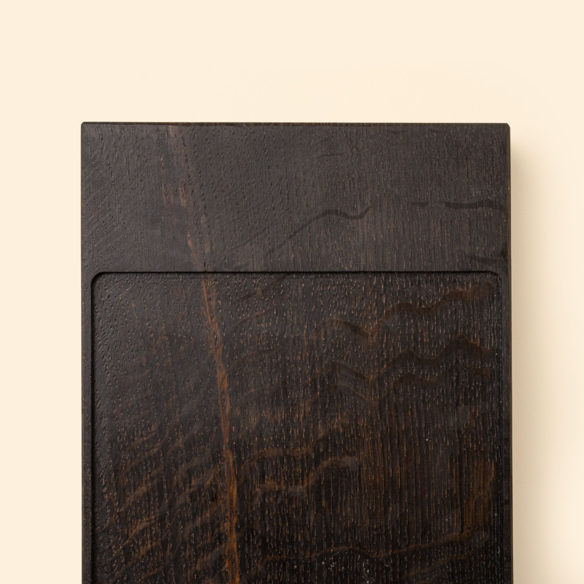 Close up of the end of a narrow rectangle of ebonized oak wood with a vertical groove at either end