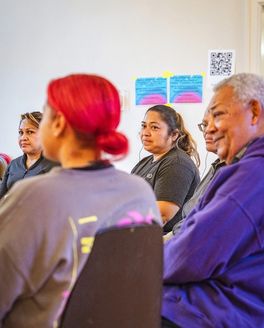 A diverse group of people gathered in a circle in the middle of conversation.